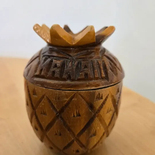 A hand-carved wooden pineapple trinket box with HAWAII carved on the lid